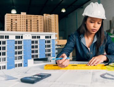 femme-afro-americaine-dans-un-casque-de-securite-travaillant-pres-du-modele-de-construction